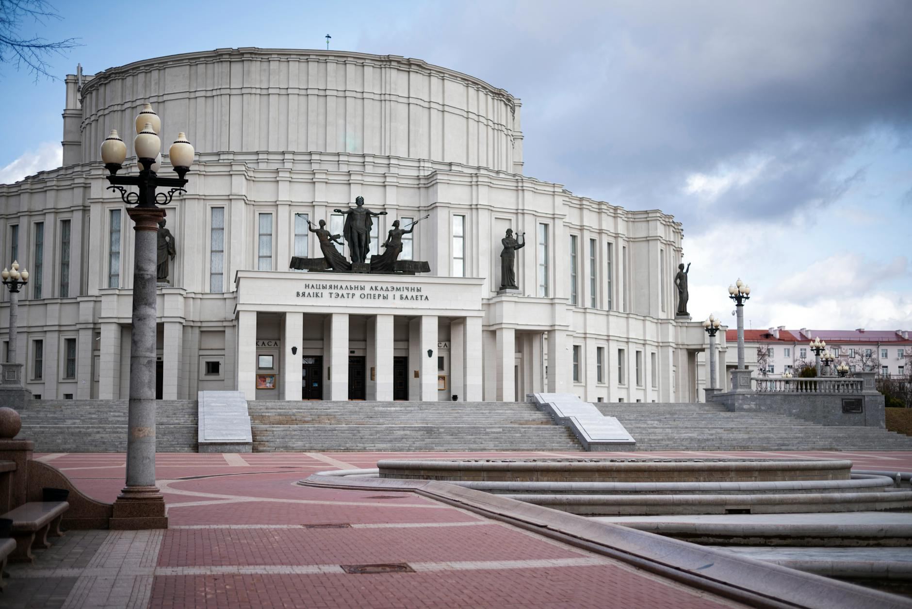 The grand facade of the Minsk National Academic Opera and Ballet Theatre stands majestically against a cloudy sky.