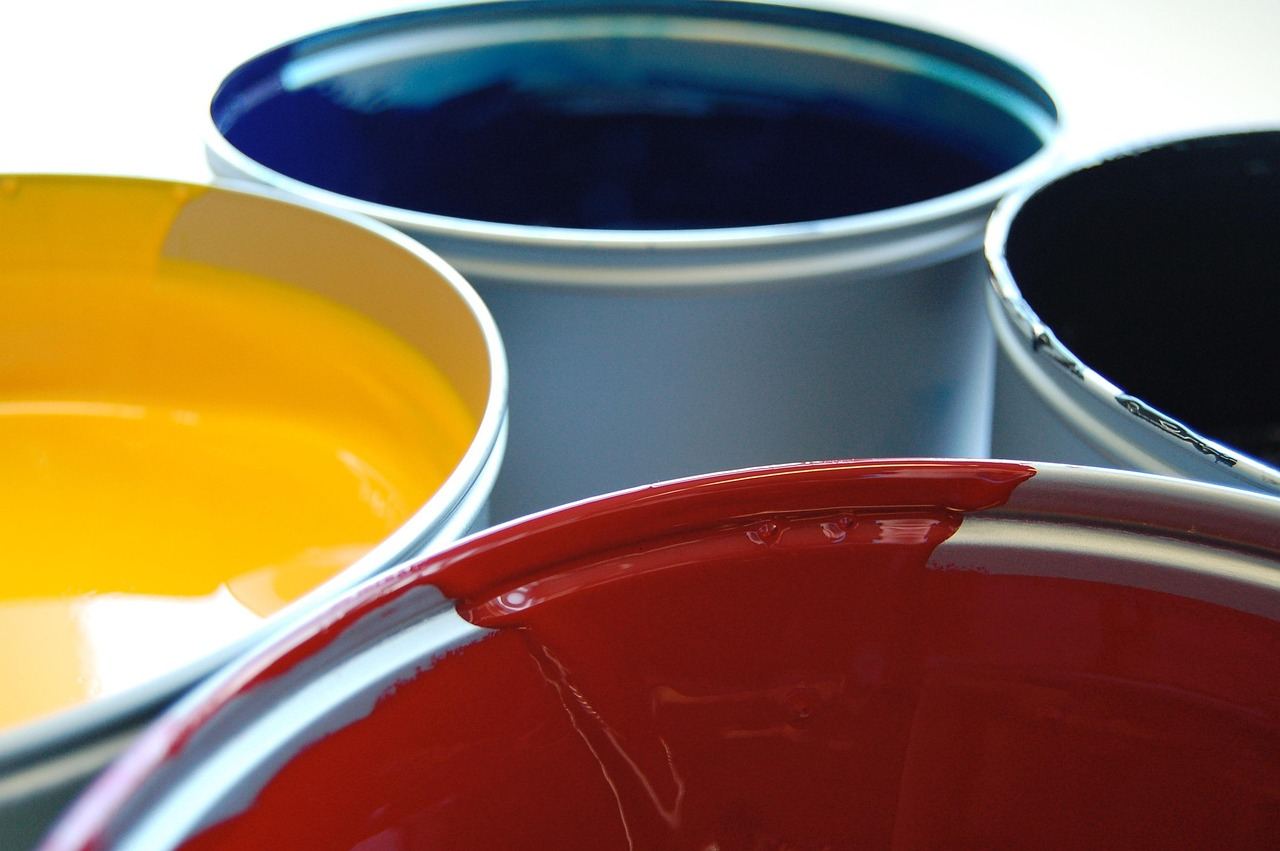 Four paint cans with vibrant inks, essential for linocut printing. Is Linocut Printing for you? Let's find out!