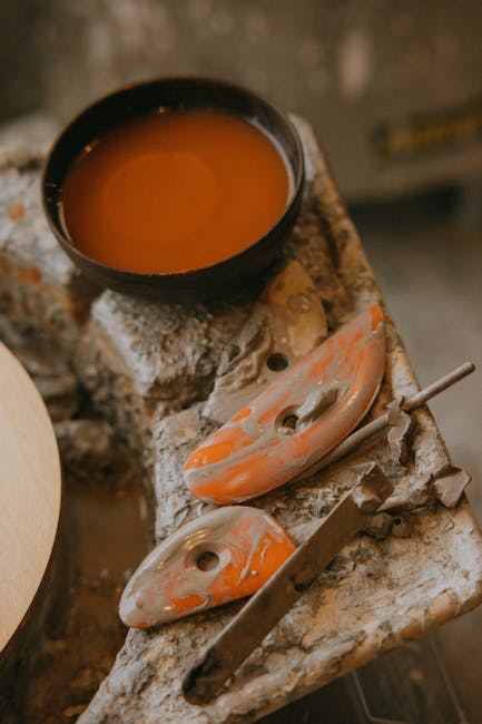 A bowl of glaze and ceramic tools on a work surface, ideal for ceramic glazing discussions.