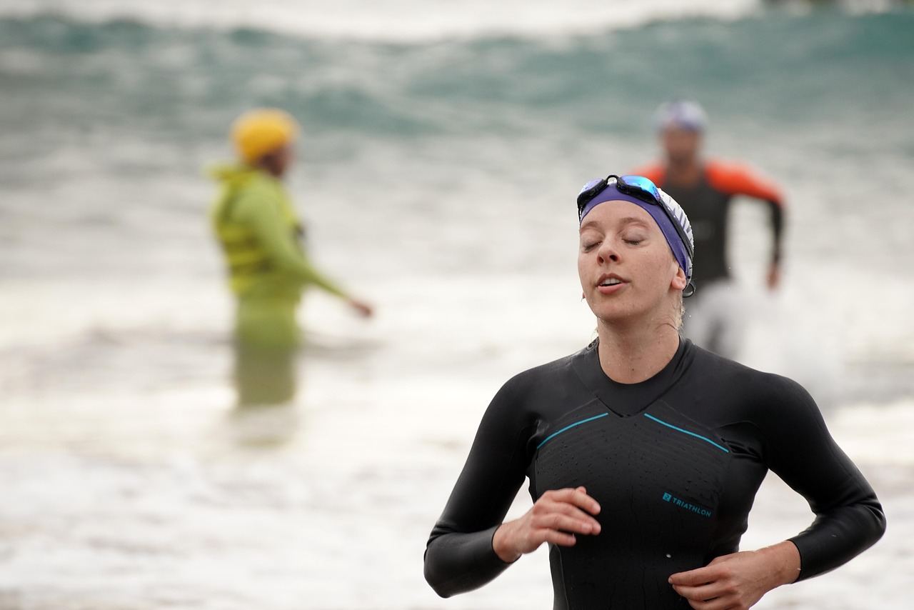 A woman in a wetsuit runs on the beach, showcasing the spirit of triathlon. Is Triathlon for you? Let's find out!