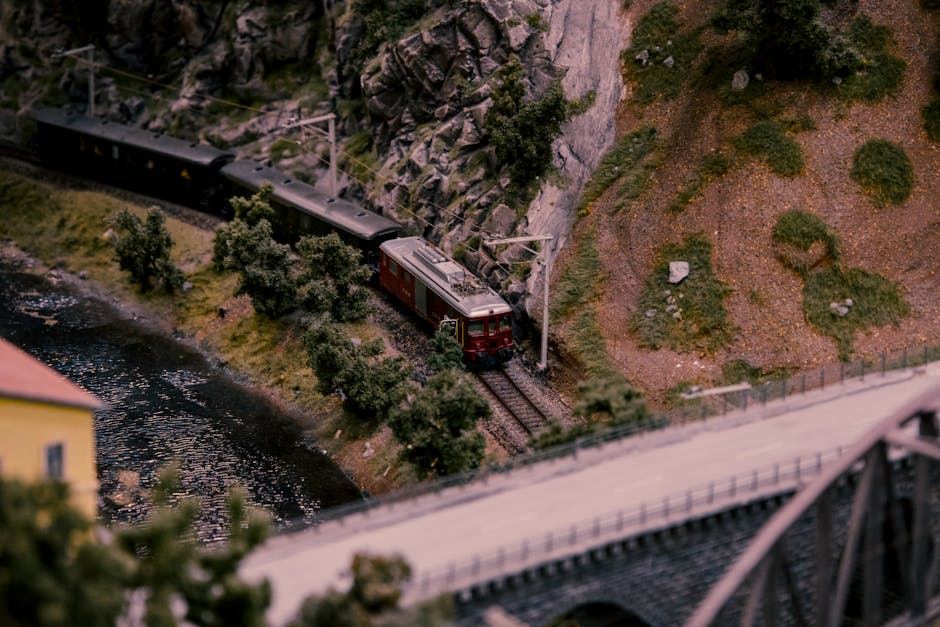 A miniature train navigating through a detailed terrain with rocks, trees, and water, showcasing terrain building.