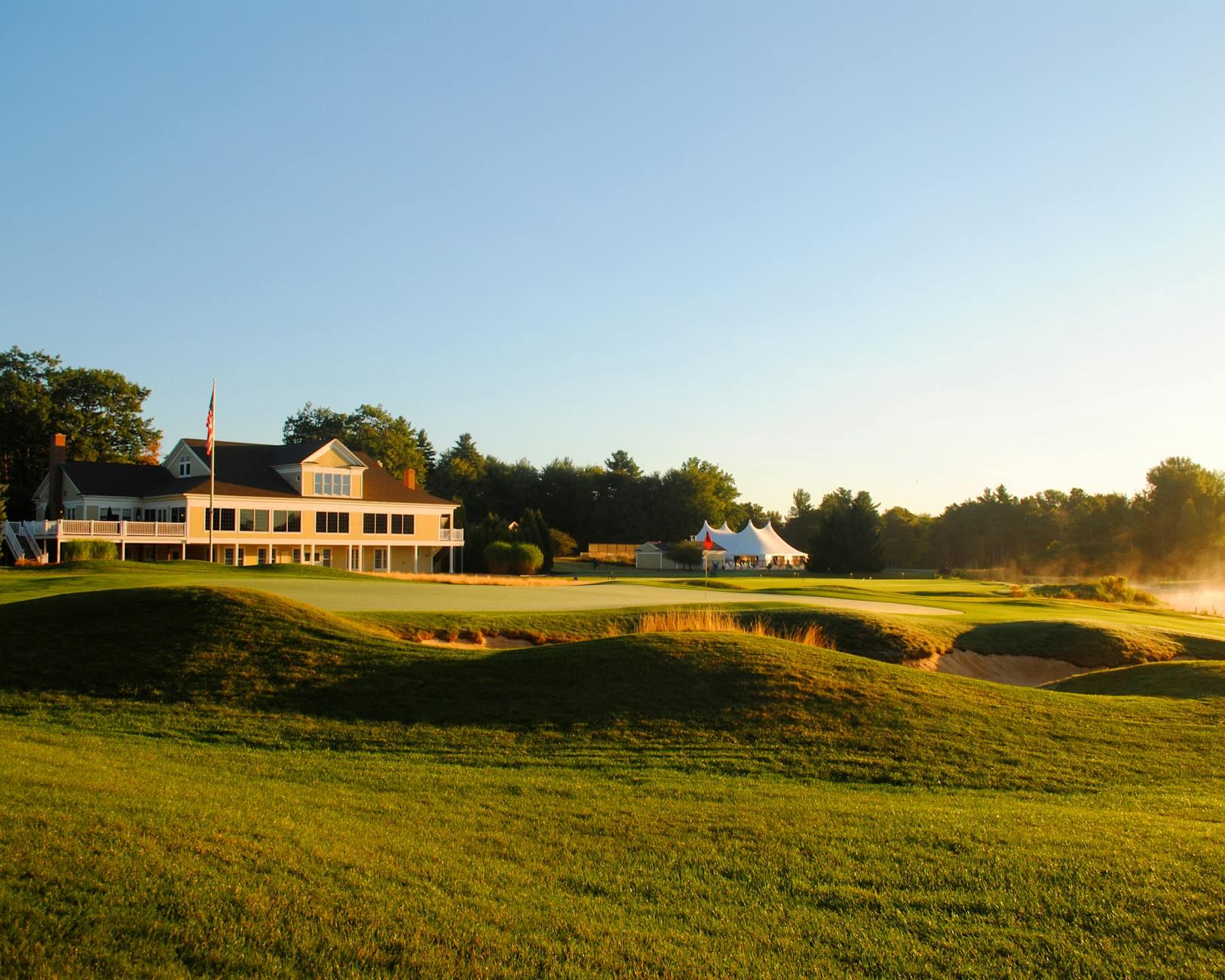 A peaceful golf course landscape with a clubhouse and morning sunlight.