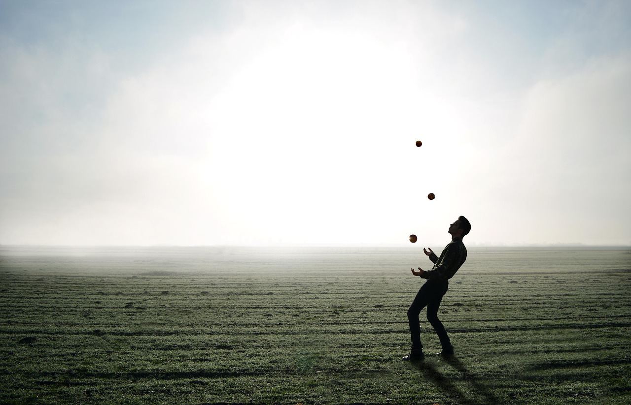 A juggler skillfully tosses balls in a foggy field, embodying the spirit of 'Is Juggling for you? Let's find out!'