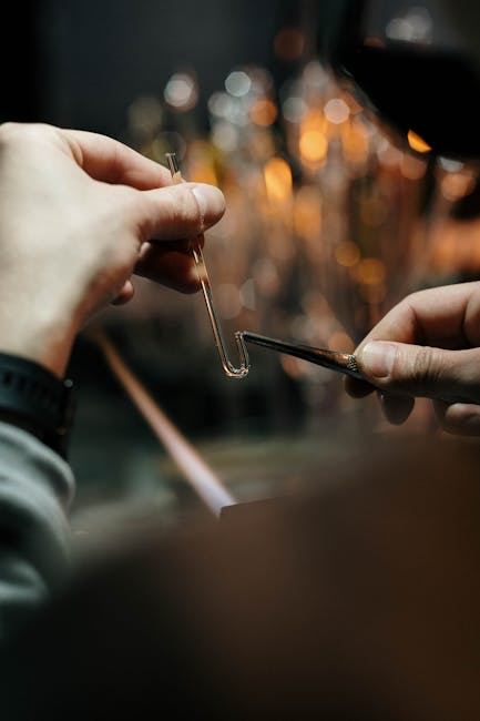 A close-up of hands shaping glass during a glassblowing process, showcasing craftsmanship and artistry.