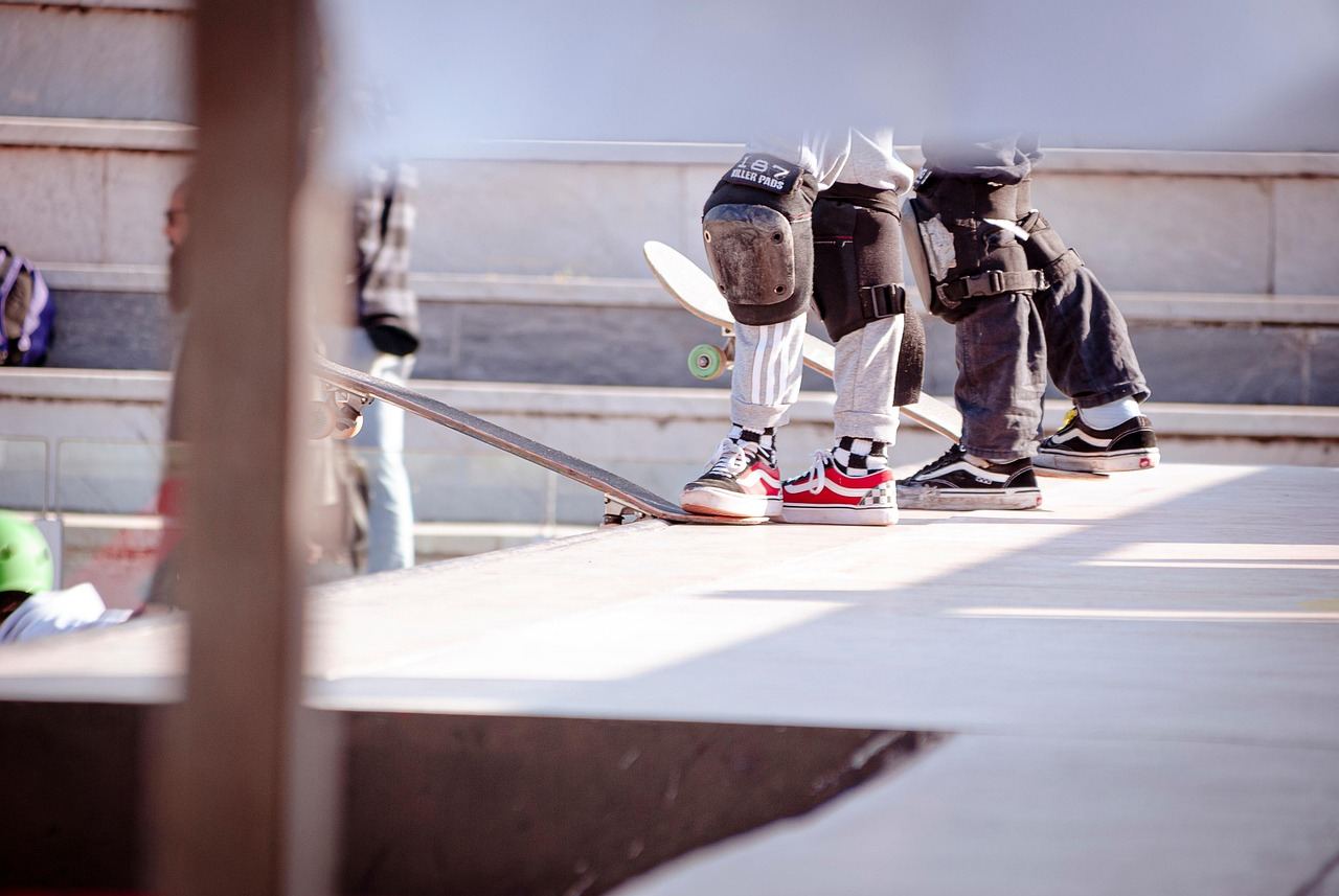 A vibrant skate park filled with skaters performing tricks on ramps and rails under a clear blue sky.