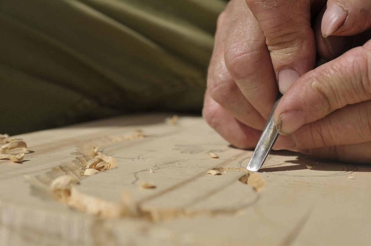 A skilled carpenter meticulously shaping wood with hand tools in a sunlit workshop filled with various timber pieces.