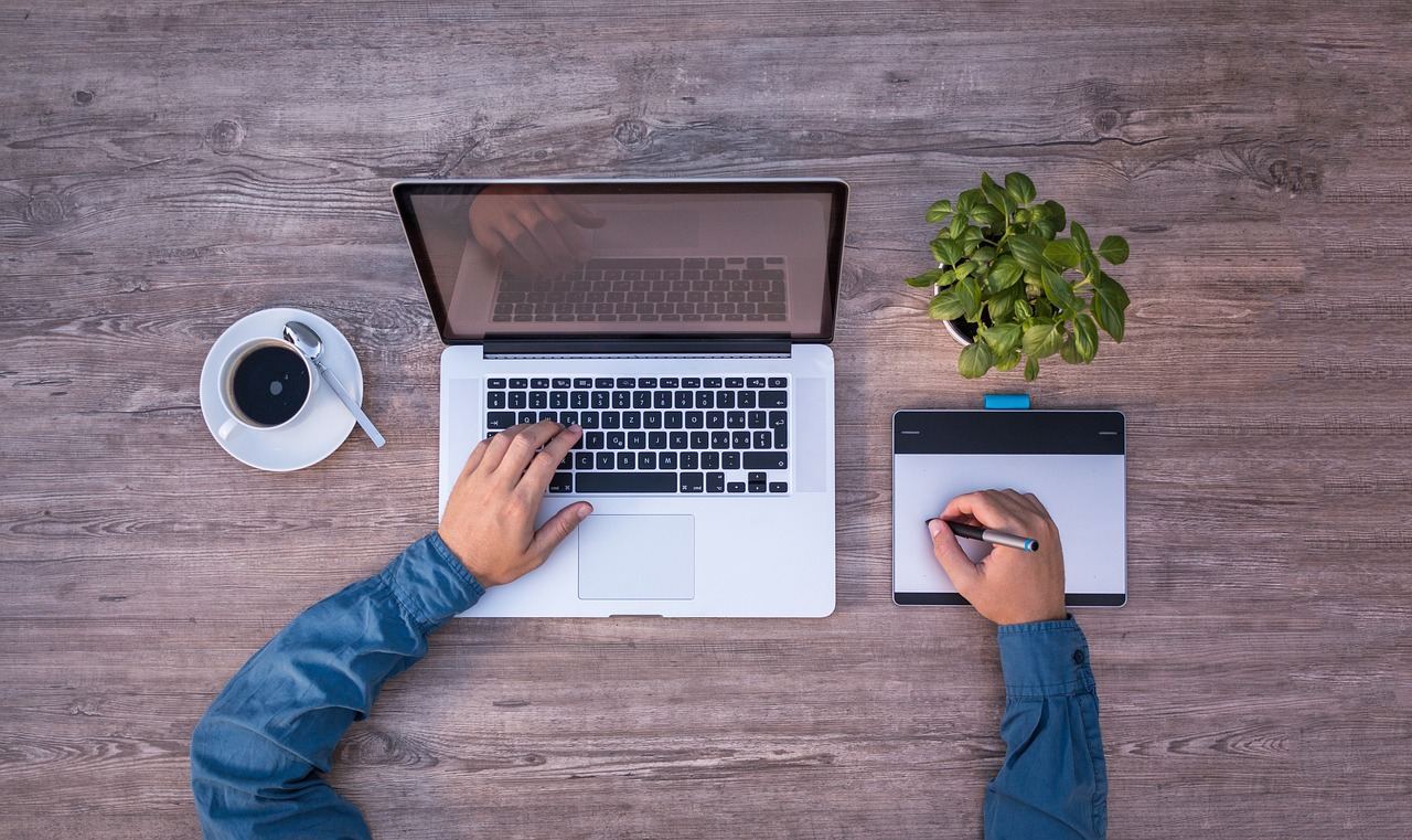 A sleek laptop on a wooden desk, displaying vibrant design software and colorful branding concepts.