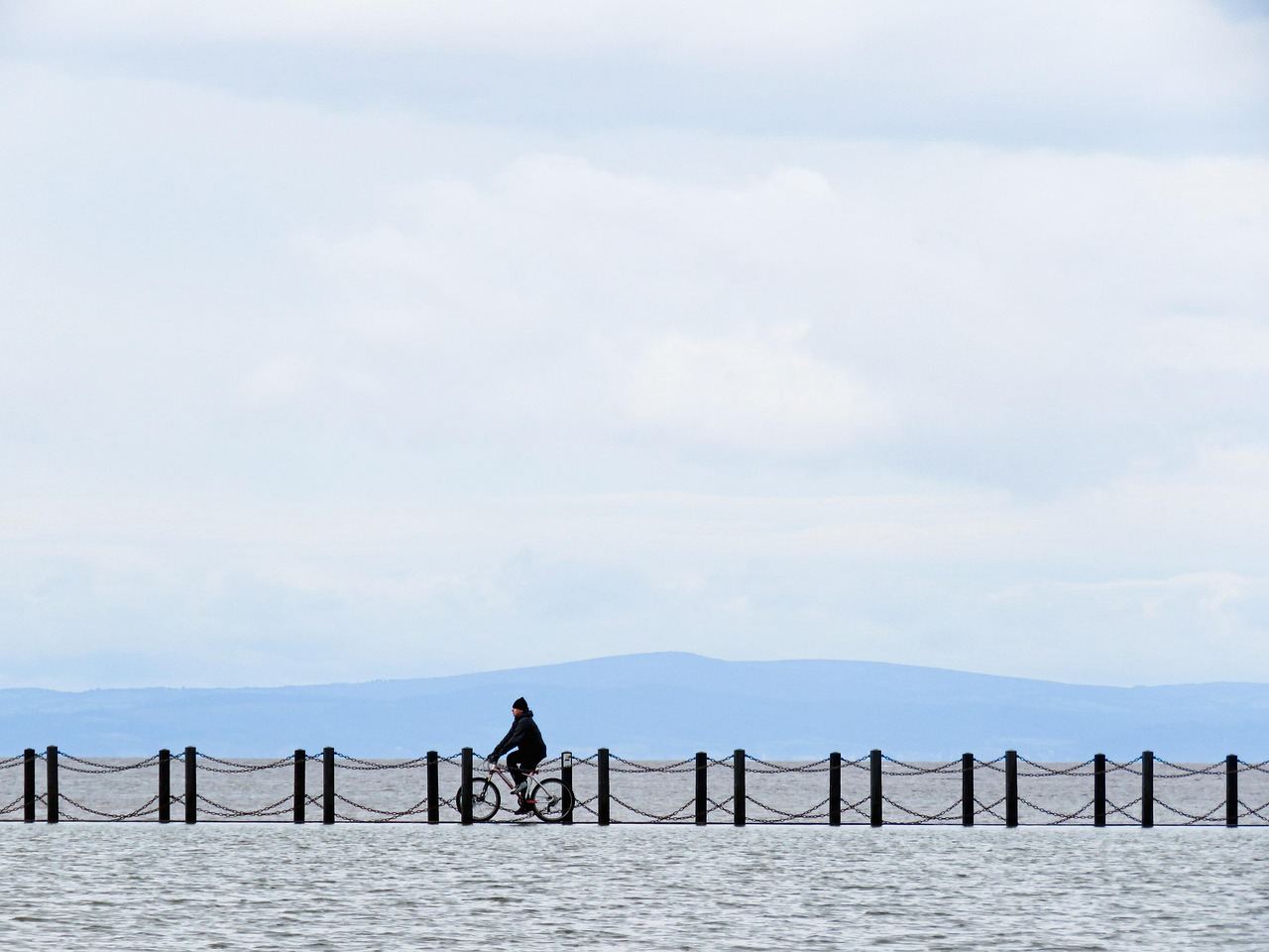 A cyclist rides along a pier, embodying the spirit of adventure in 'Is Cycle Touring for you? Let's find out!'