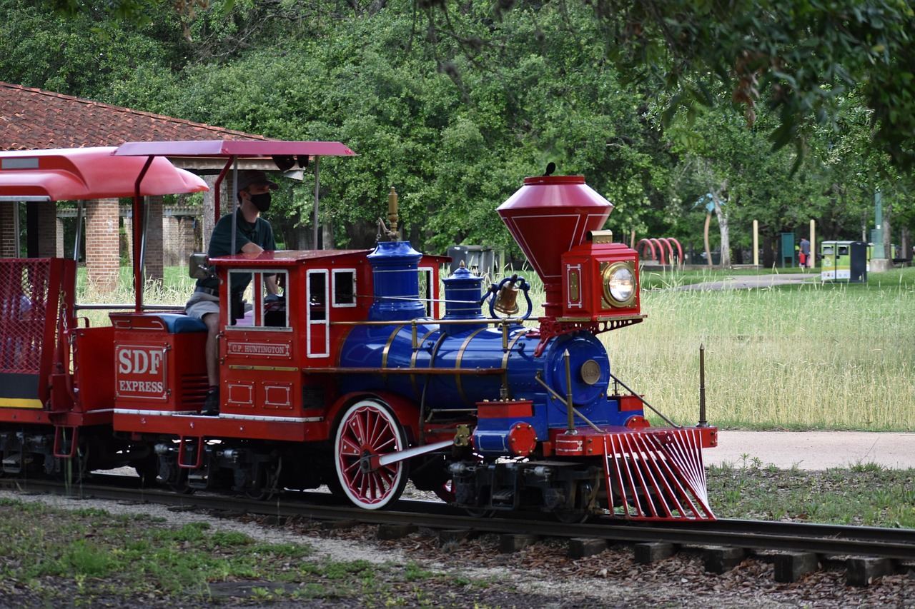 A colorful miniature train chugs along a winding track, surrounded by vibrant greenery and cheerful children enjoying the ride.