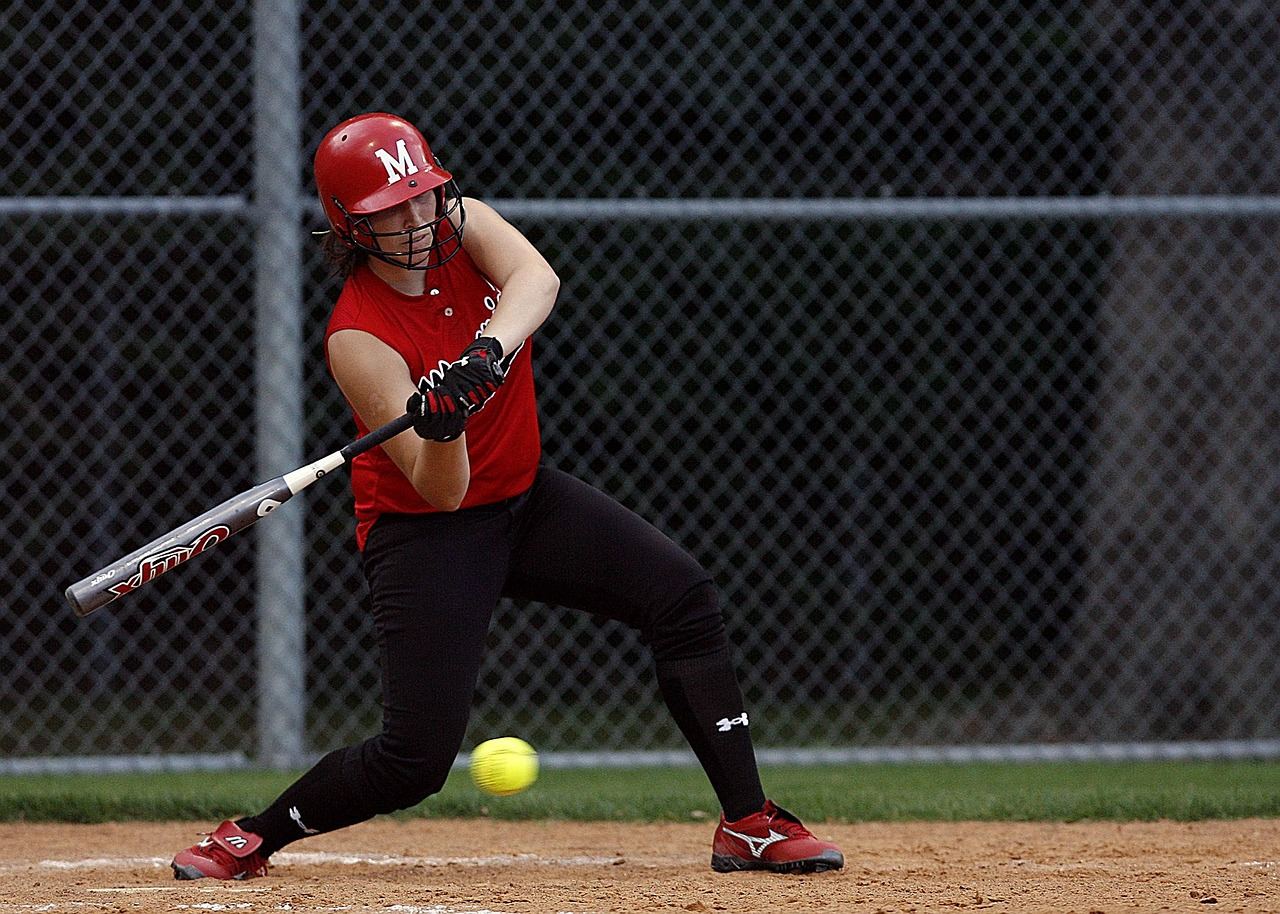 A player swings a bat at a slowpitch softball, illustrating the excitement of the game. Is Slowpitch Softball for you? L