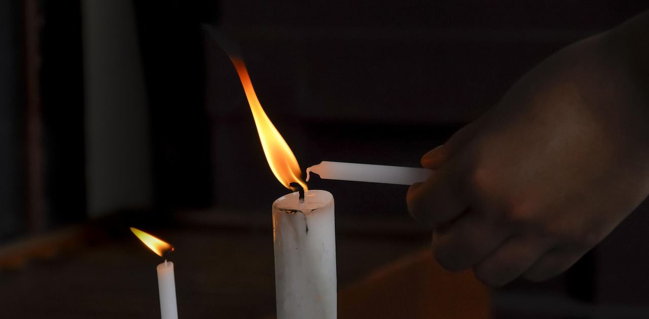 Soft, flickering candlelight casts a warm glow, illuminating a cozy space filled with various handmade candles.