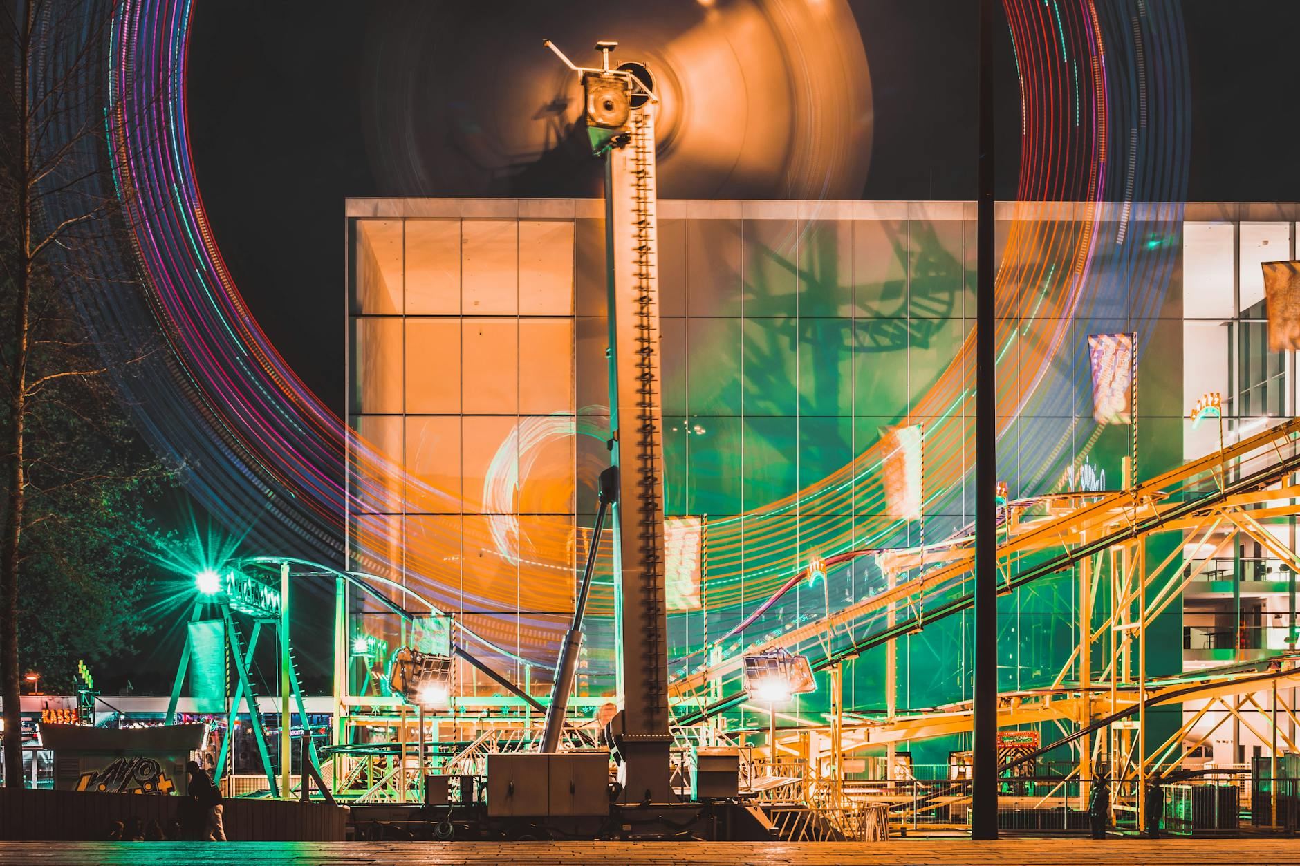 Colorful nighttime image of a fairground ride in Almere, Netherlands with motion blur effects.