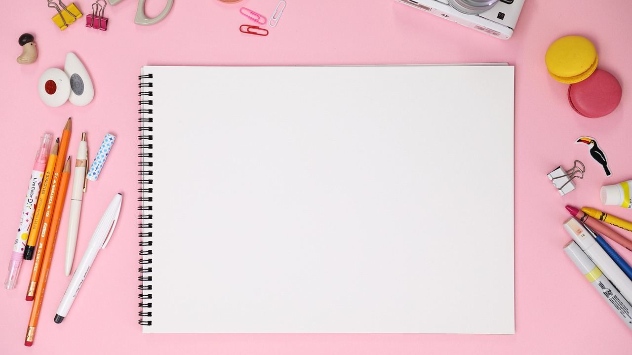A vibrant pink background featuring various drawing tools like pencils, erasers, and sketchbooks arranged artistically.