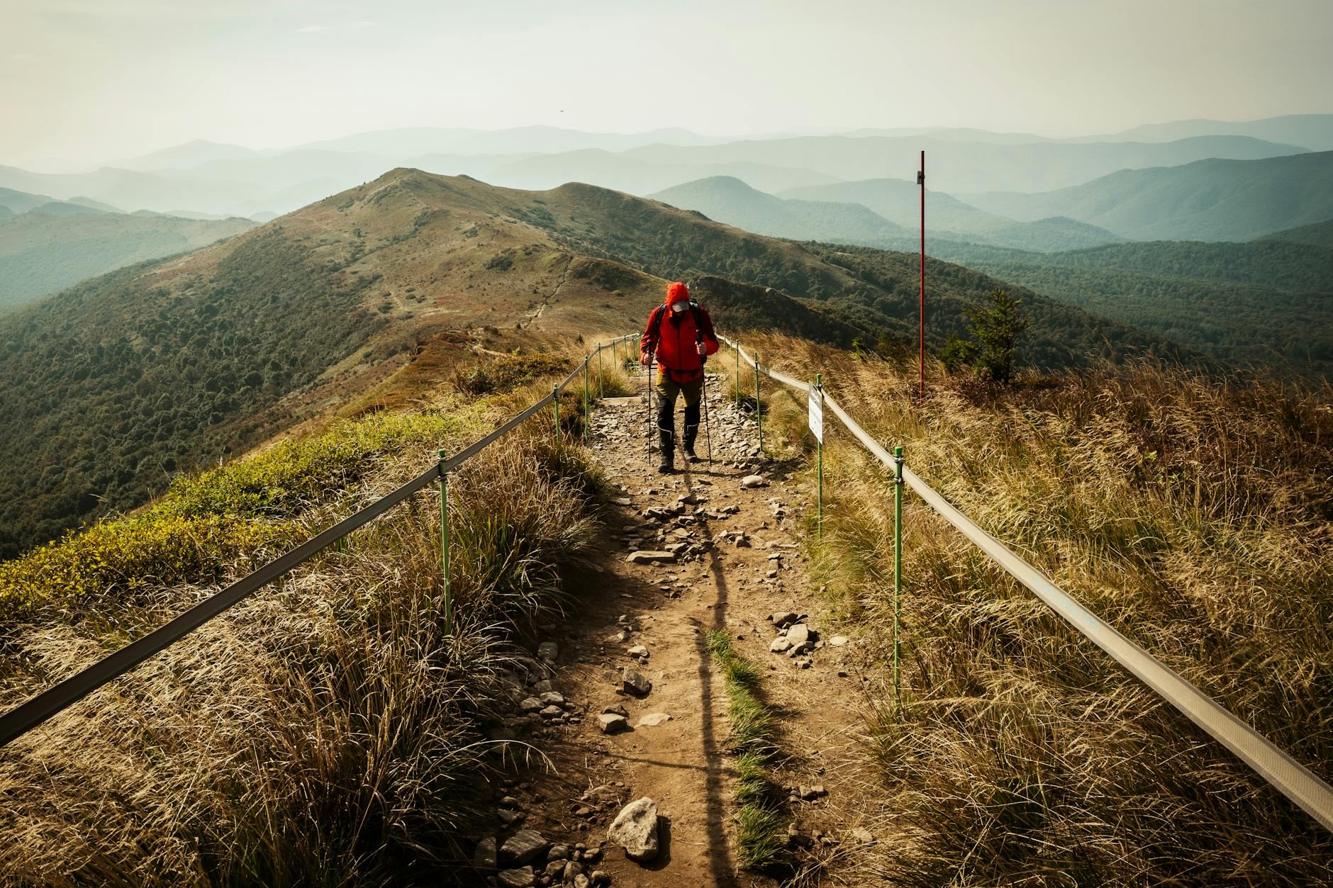 Adventurous hiker with a backpack walking a mountain trail surrounded by scenic landscapes during autumn.