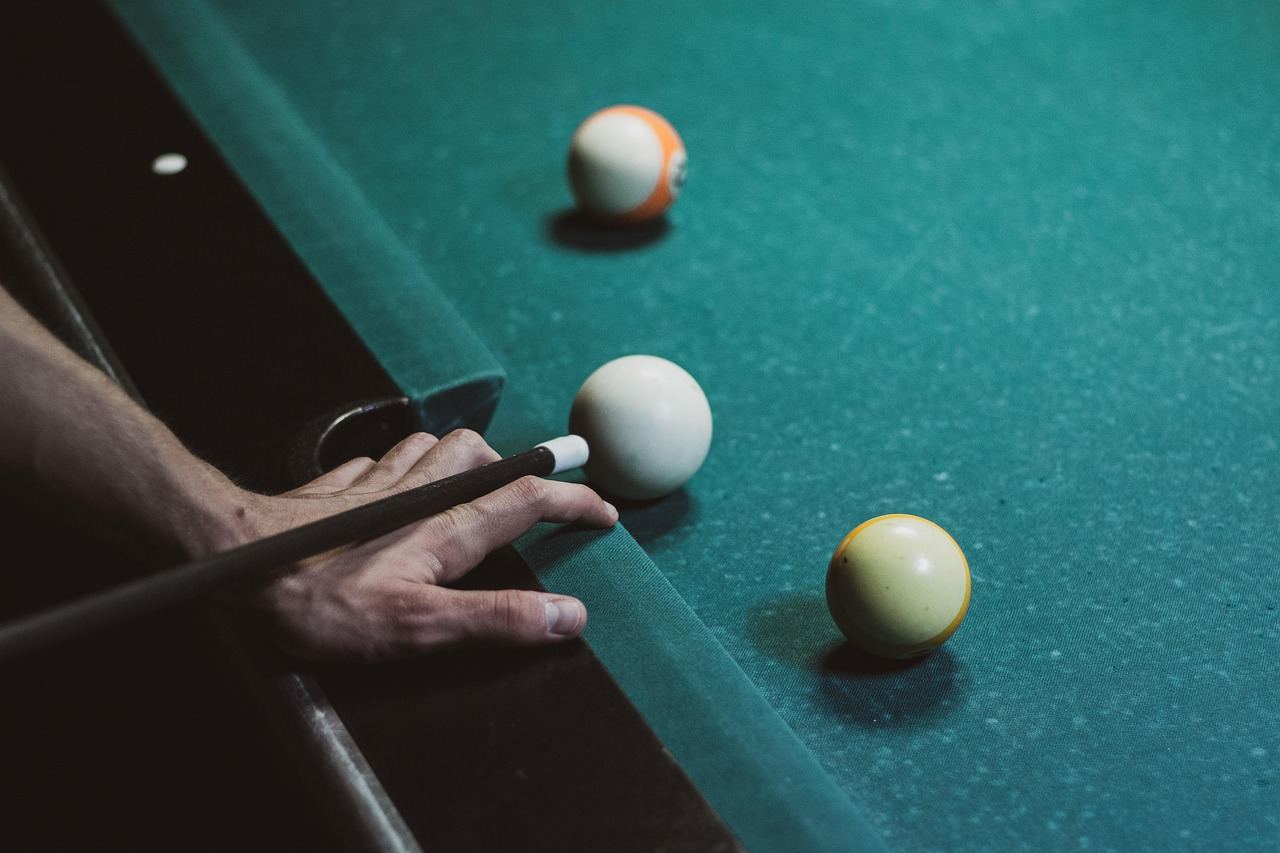 A player prepares to strike a white ball in Carom Billiards. Is Carom Billiards for you? Let's find out!