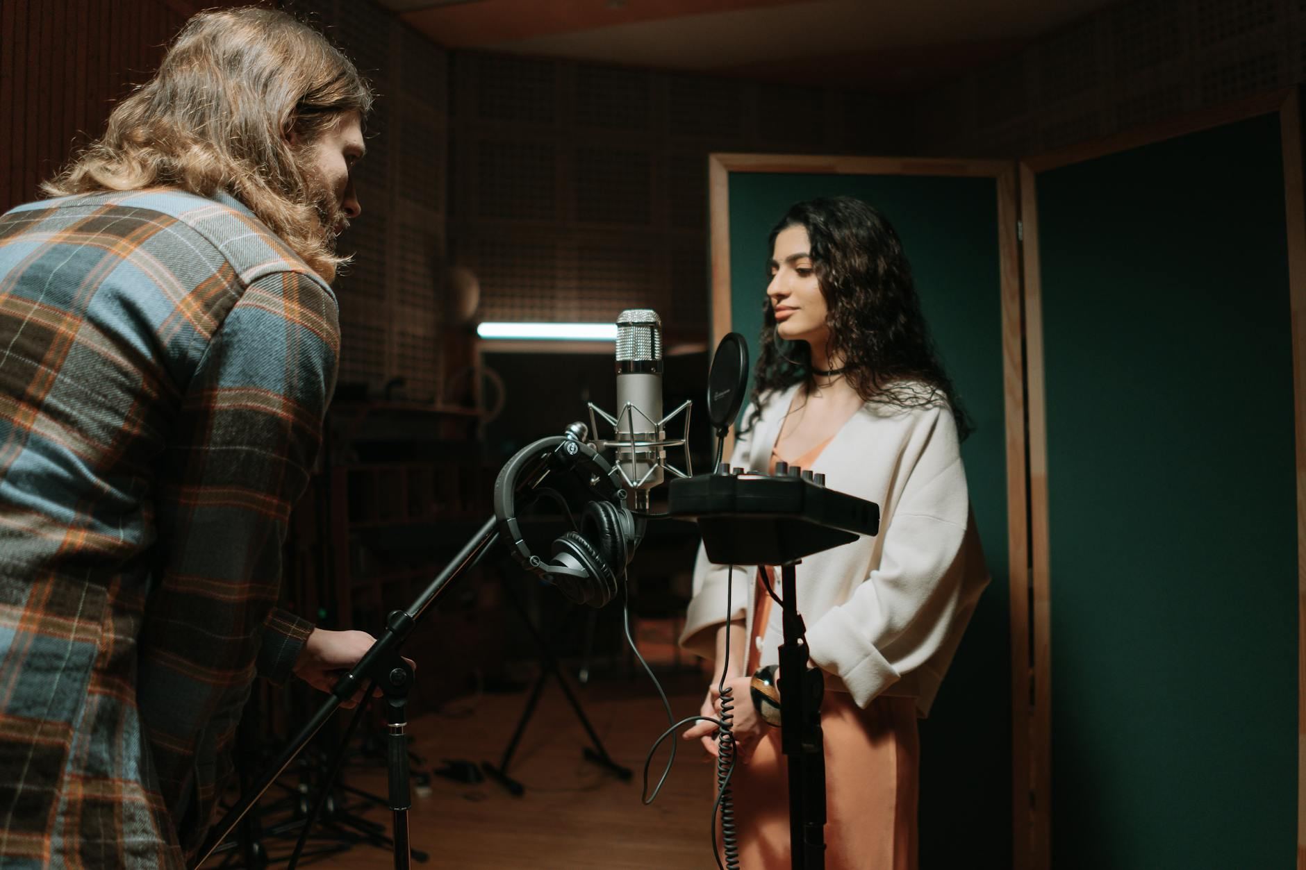 A woman recording vocals in a professional music studio setting.