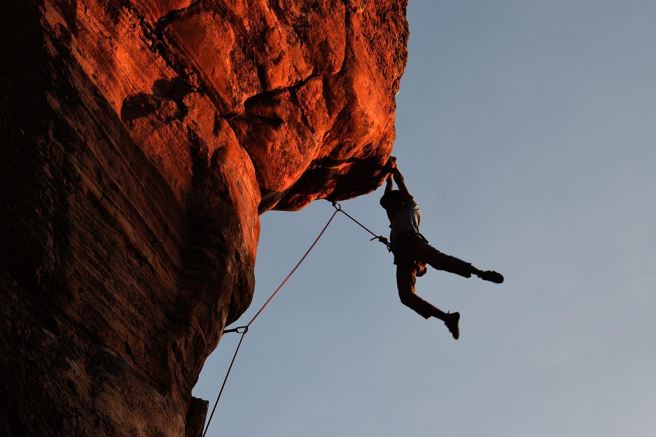 A climber skillfully ascends a rugged rock face, showcasing determination and strength against a backdrop of natural beauty.