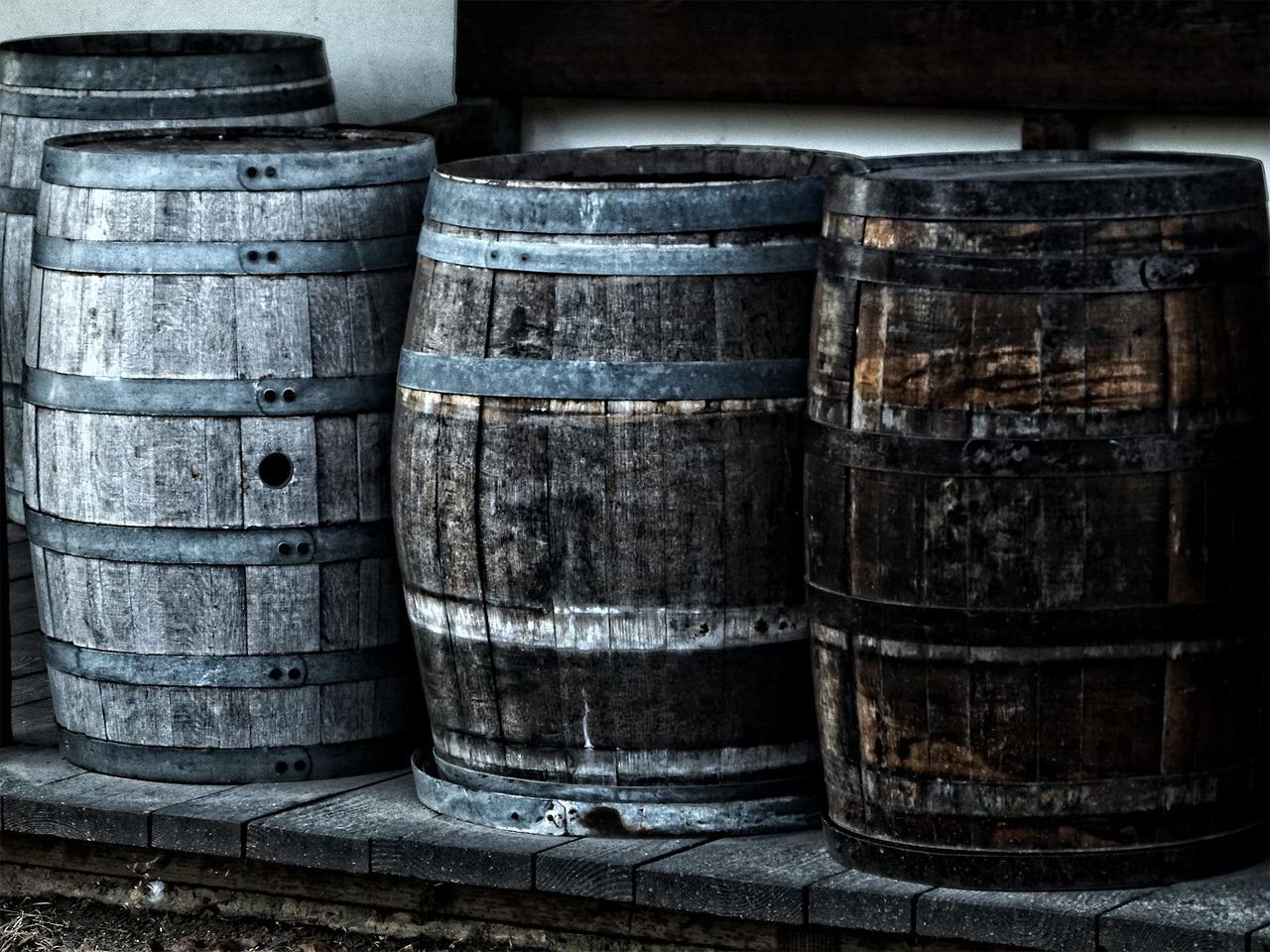 A row of aged wooden barrels stacked in a dimly lit distillery, exuding a rich, amber hue.