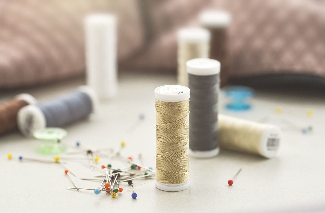 Spools of thread and pins scattered on a table, perfect for exploring applique techniques. Is Applique for you? Let's fi