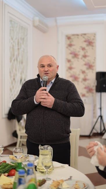 A man speaking into a microphone at an event, demonstrating public speaking skills.
