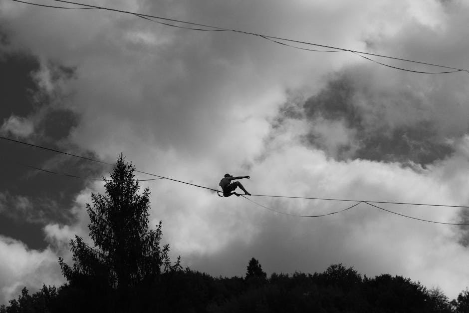 A person highlining on a rope against a backdrop of clouds and trees.