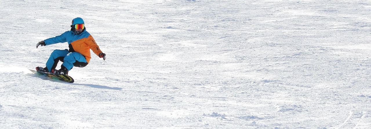 A snowboarder glides down a snowy slope, showcasing the thrill of alpine snowboarding. Is Alpine Snowboarding for you? L