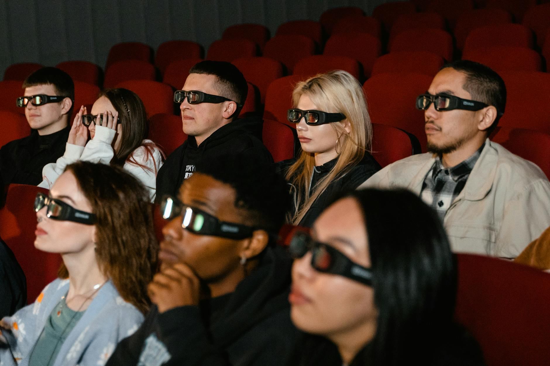 A lively audience of diverse adults immerses themselves in a thrilling 3D movie experience within a cozy theater.