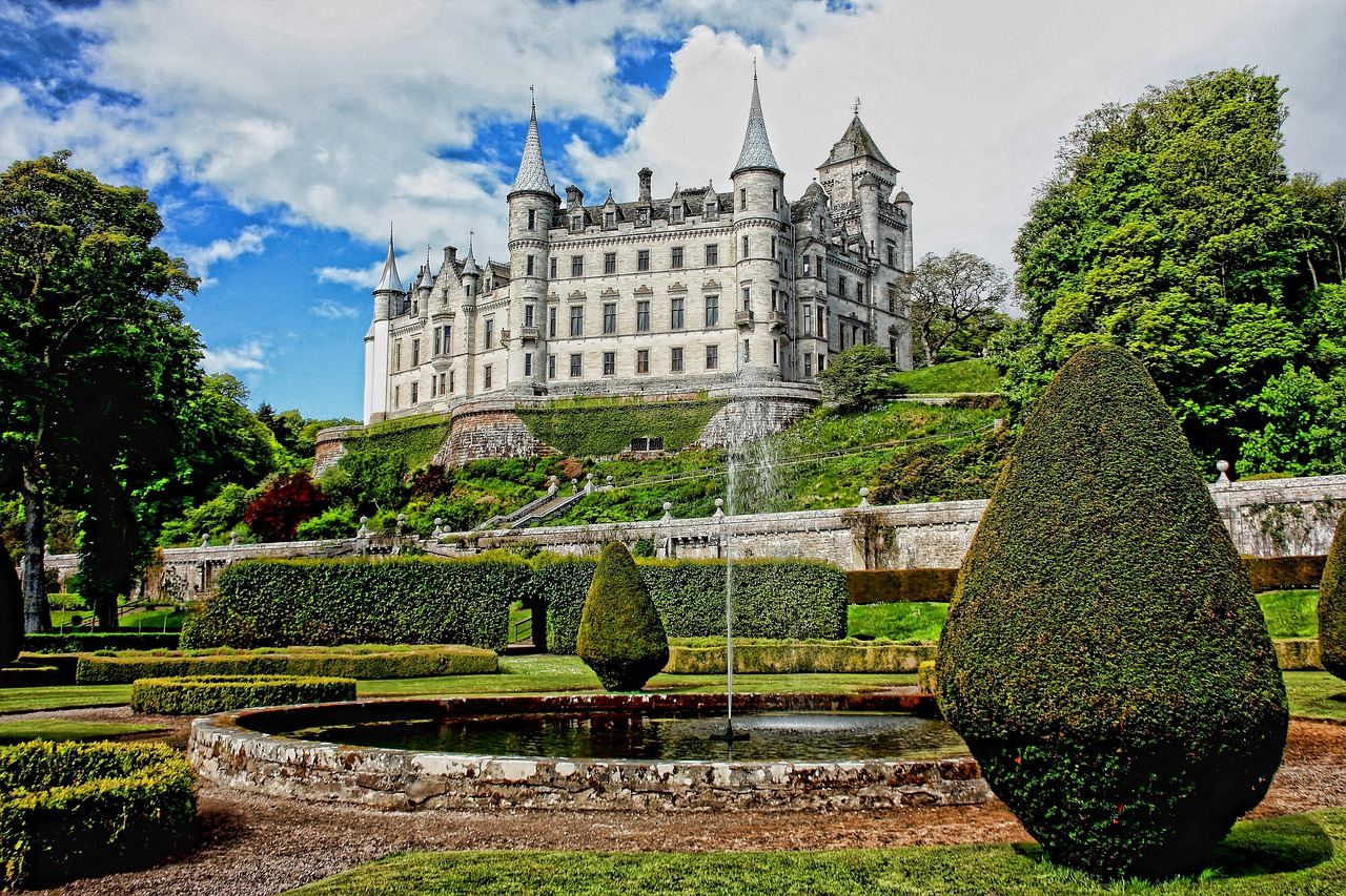 A beautifully manicured garden at Dunrobin Castle, featuring vibrant flower beds and lush greenery against a historic backdrop.