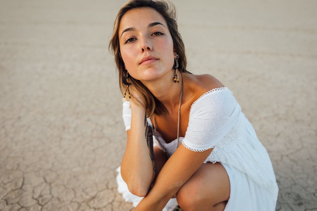 A woman in a white dress poses thoughtfully, exploring themes of identity in fashion photography.