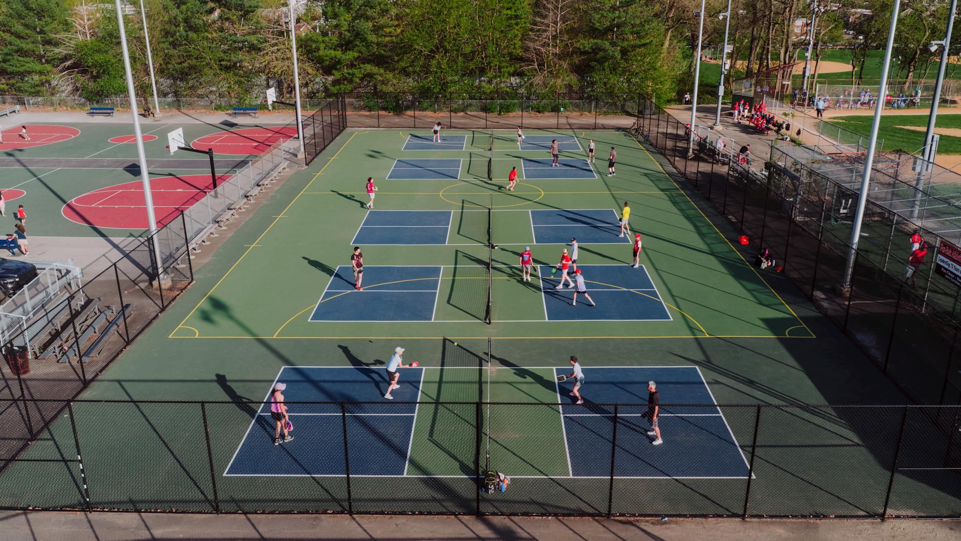 A vibrant pickleball match unfolds on outdoor courts in Philadelphia, bathed in sunlight, showcasing players in action.