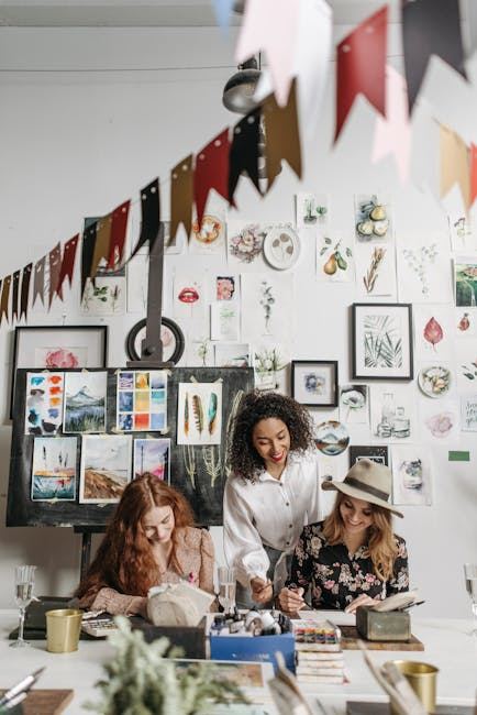Three women engaged in gouache painting, surrounded by colorful artworks and creative supplies.