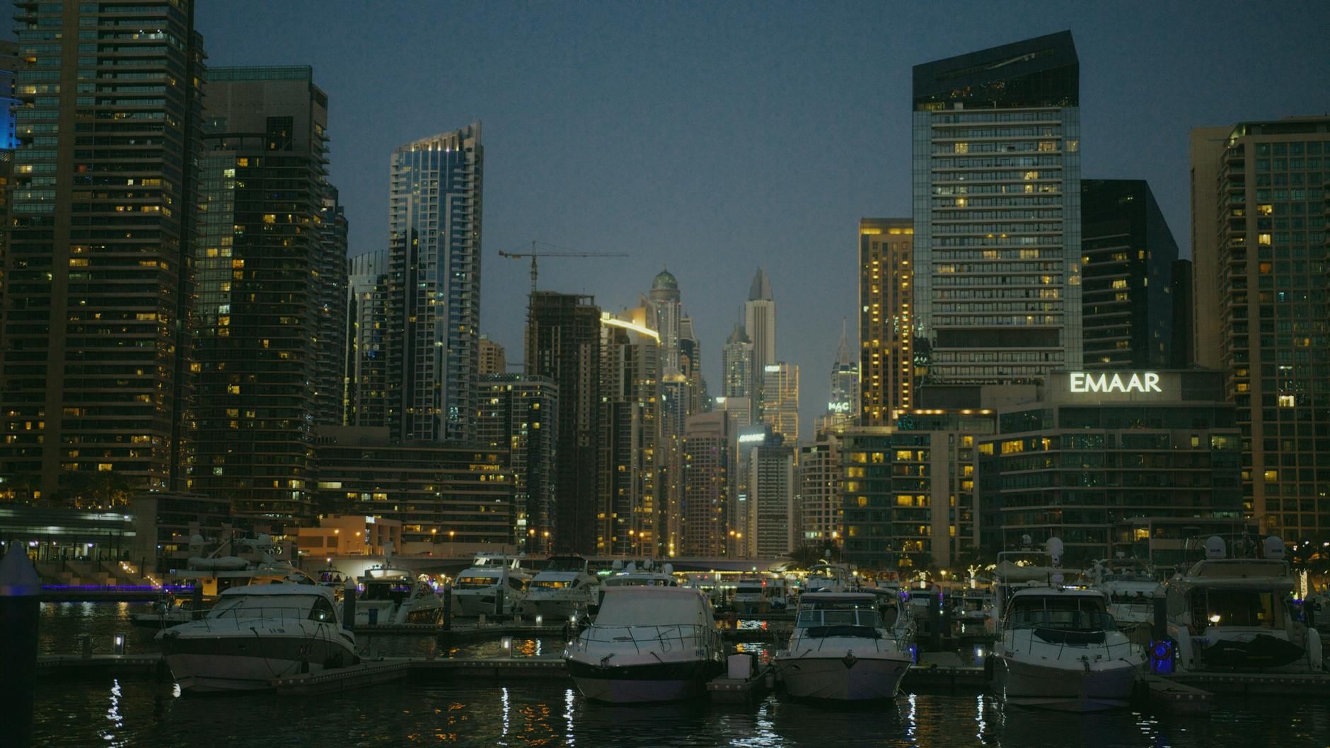 Captivating nighttime cityscape of Dubai Marina with luxury yachts and towering skyscrapers.