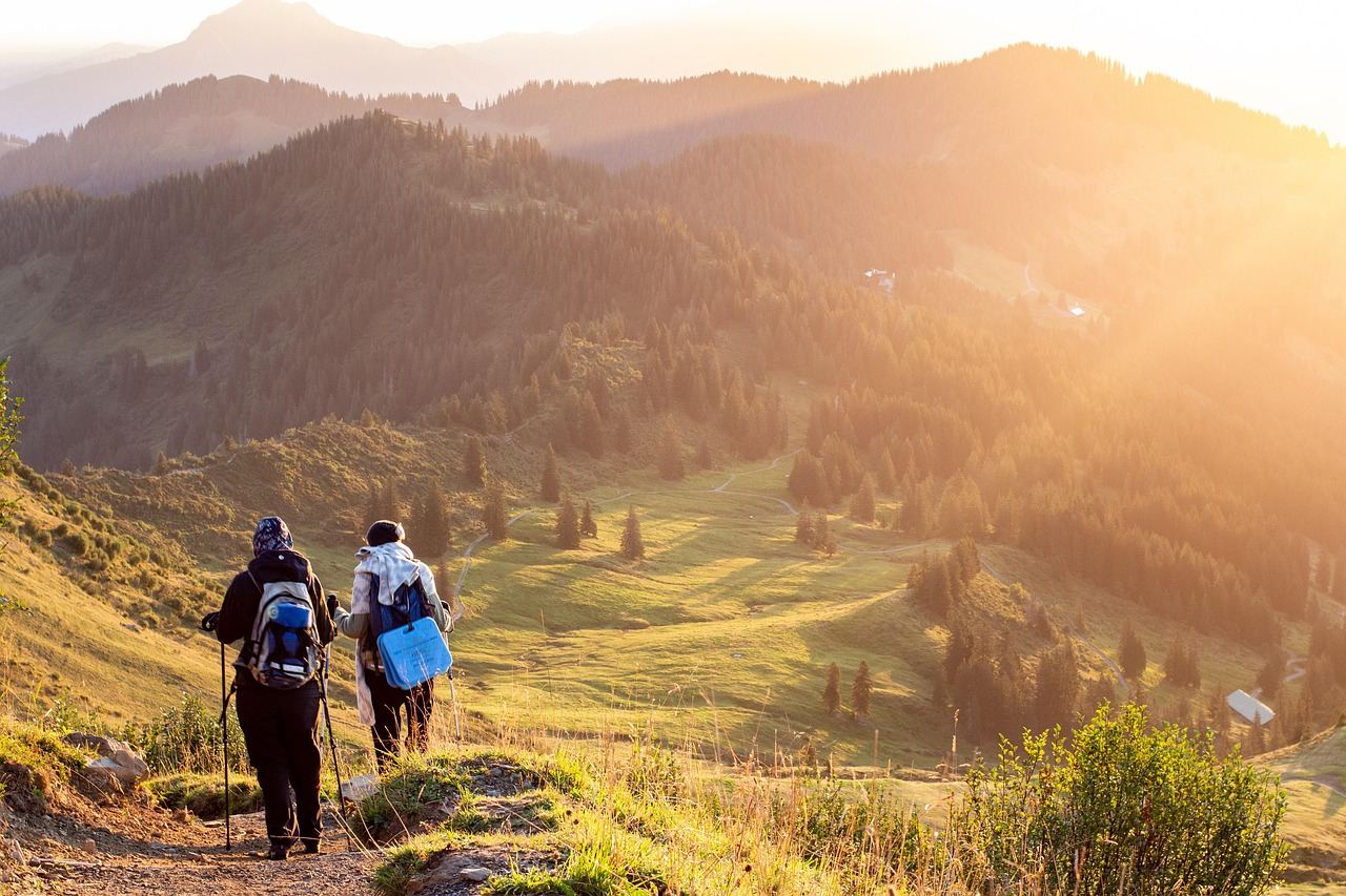 Two hikers trek through a scenic landscape at sunset, embodying adventure travel. Is Adventure Travel for you? Let's fin