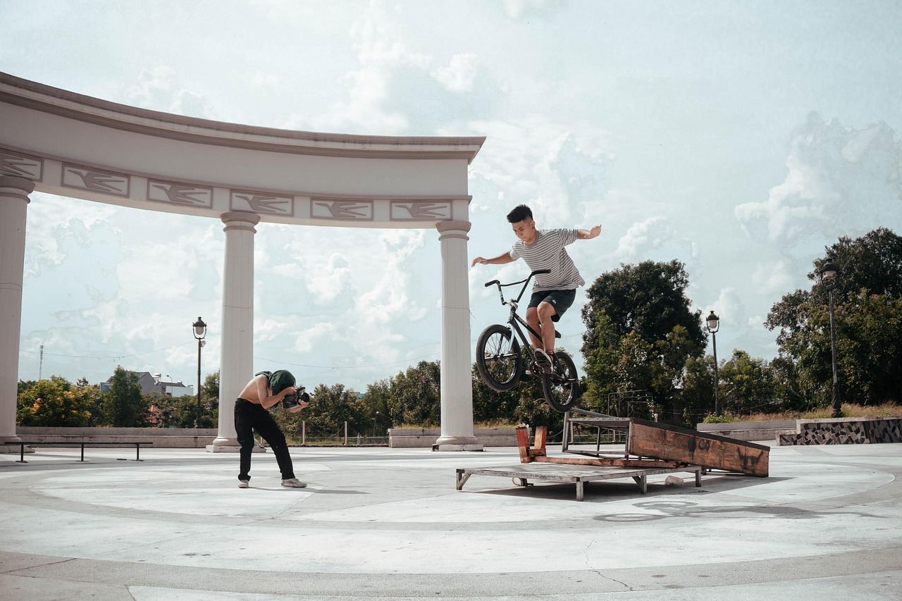 A BMX rider performs an impressive trick mid-air against a vibrant blue sky, showcasing skill and excitement.