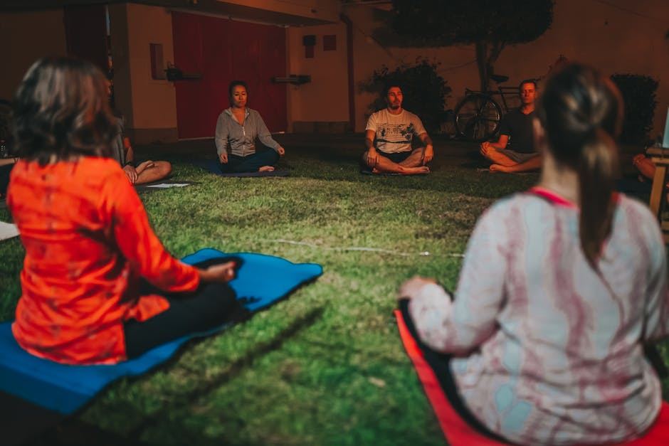 Group of people meditating on grass, illustrating the concept of guided meditation.