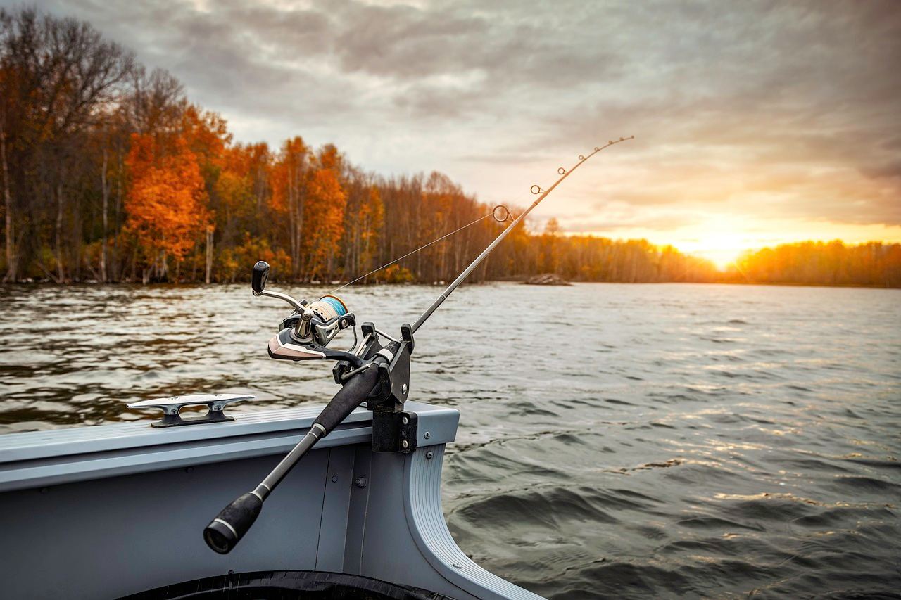 A fishing rod rests on a boat, ready for bass fishing as the sun sets. Is Bass Fishing for you? Let's find out!