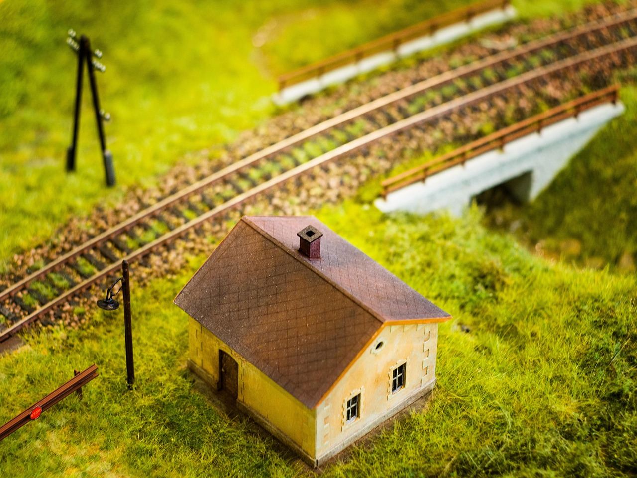 A miniature house beside train tracks, showcasing the charm of train set modeling. Is Train Set Modeling for you? Let's