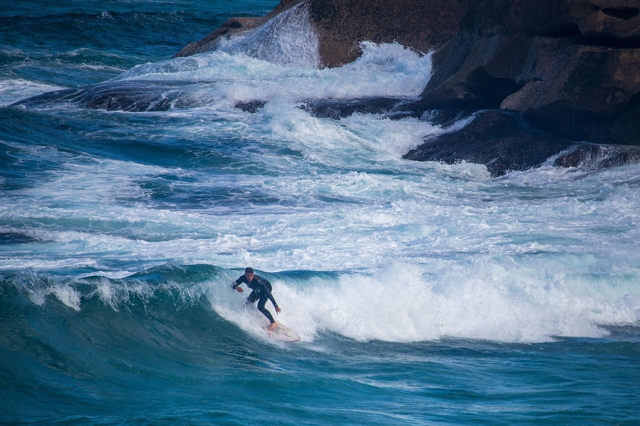 A surfer skillfully rides a vibrant wave on a longboard, showcasing balance and agility against a sunny backdrop.