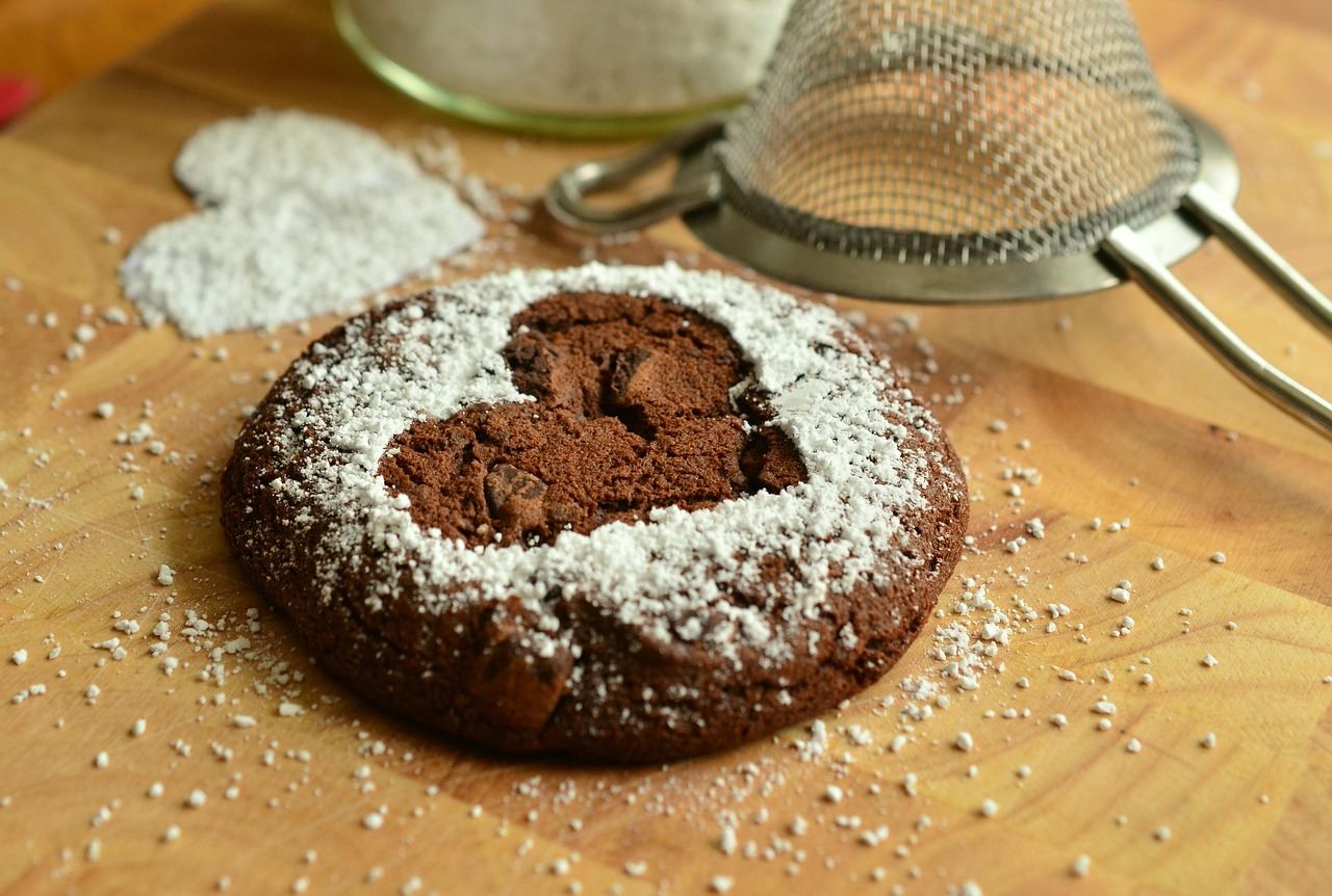 A heart-shaped chocolate cookie dusted with powdered sugar, perfect for exploring if cookie baking is for you.