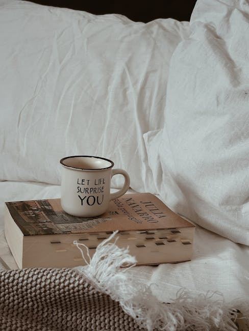 A cozy scene featuring a cup and books on a bed, suggesting a relaxing reading atmosphere.