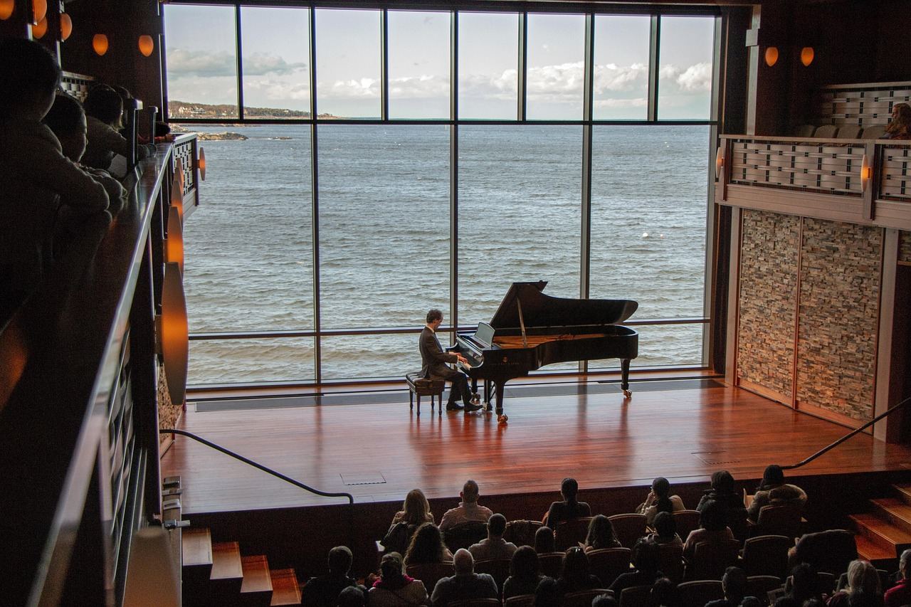 A pianist performs at a grand piano with a scenic ocean view, exploring classical music's emotional depth.