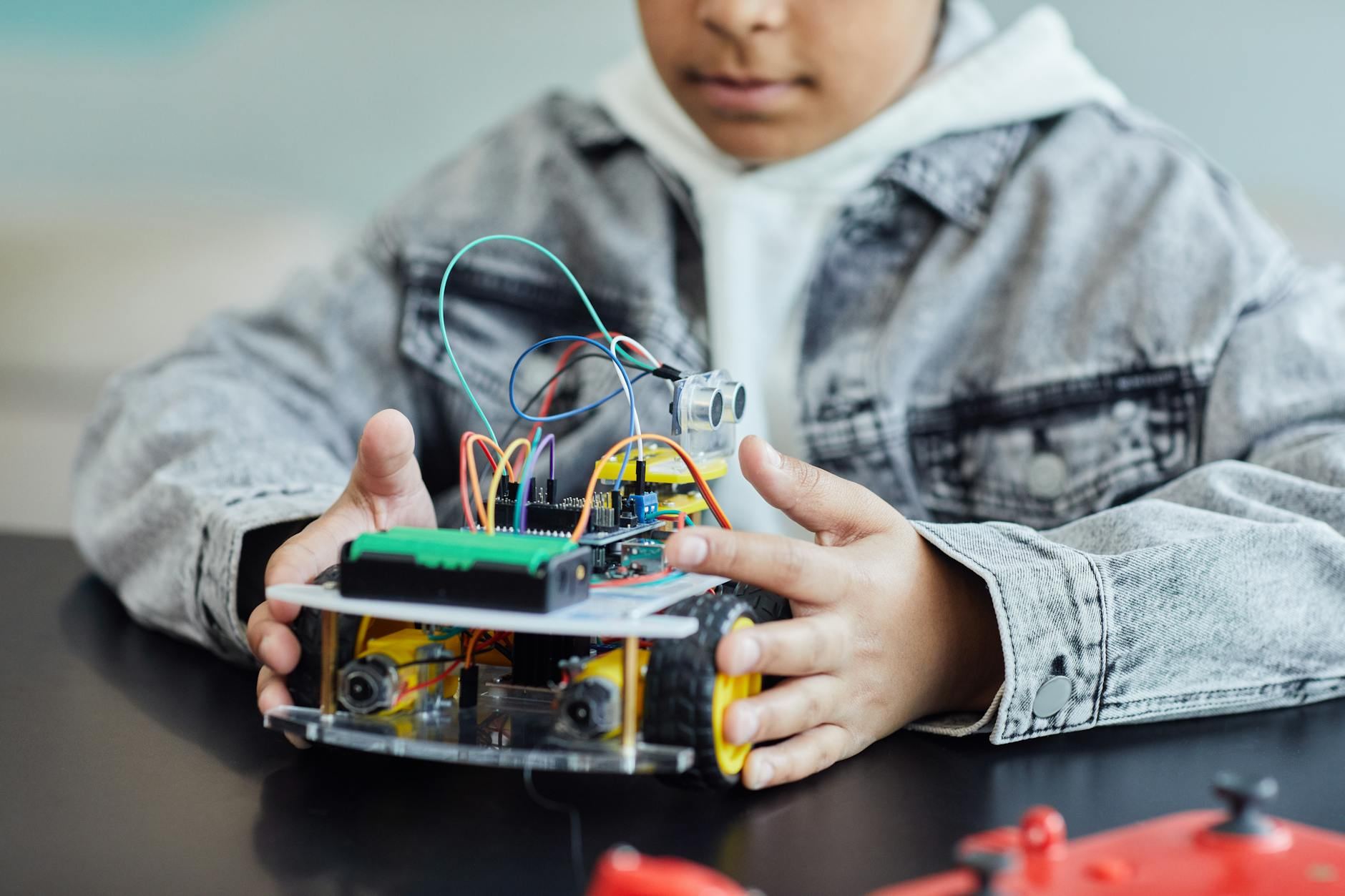 A child enthusiastically assembling a DIY robotics project, surrounded by colorful wires and wheels, embodying innovation and creativity.