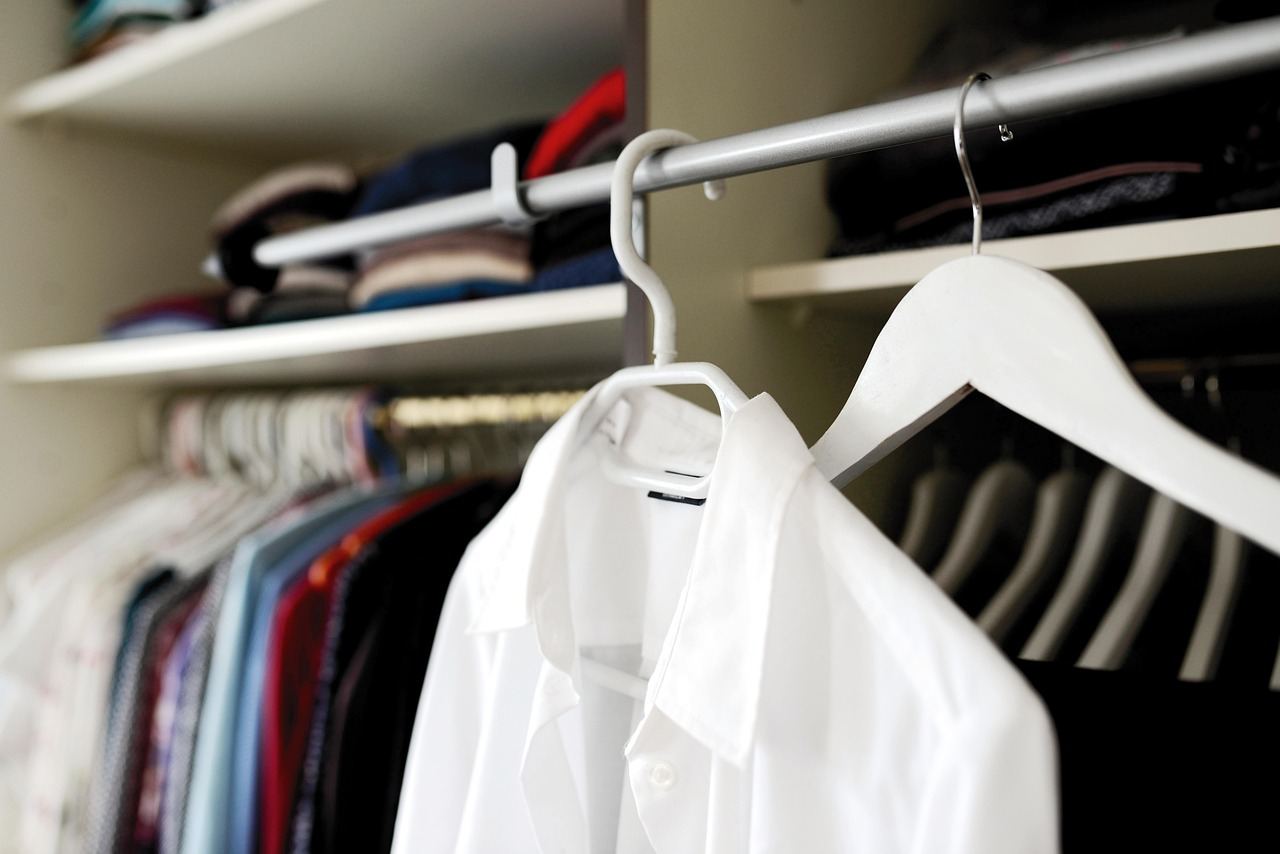 A beautifully organized wardrobe filled with neatly hung garments in various fabrics and colors, showcasing tailored clothing options.