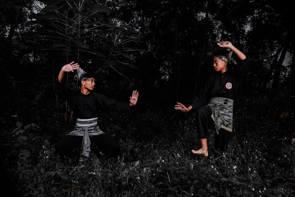 Two practitioners demonstrating Arnis techniques in a forest setting, showcasing their martial arts skills.