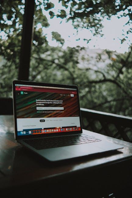 A laptop on a wooden table, surrounded by greenery, ideal for exploring 350+ websites when bored.