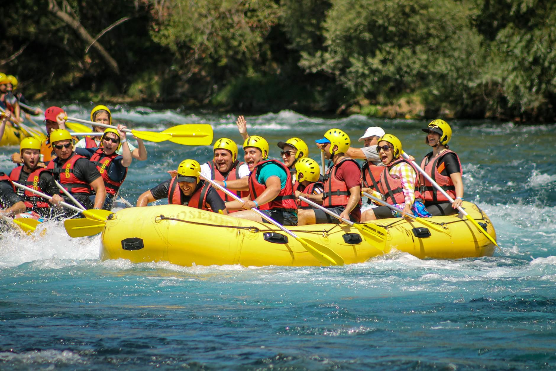 A lively group paddles together through turbulent river rapids, showcasing teamwork and excitement during their rafting adventure.