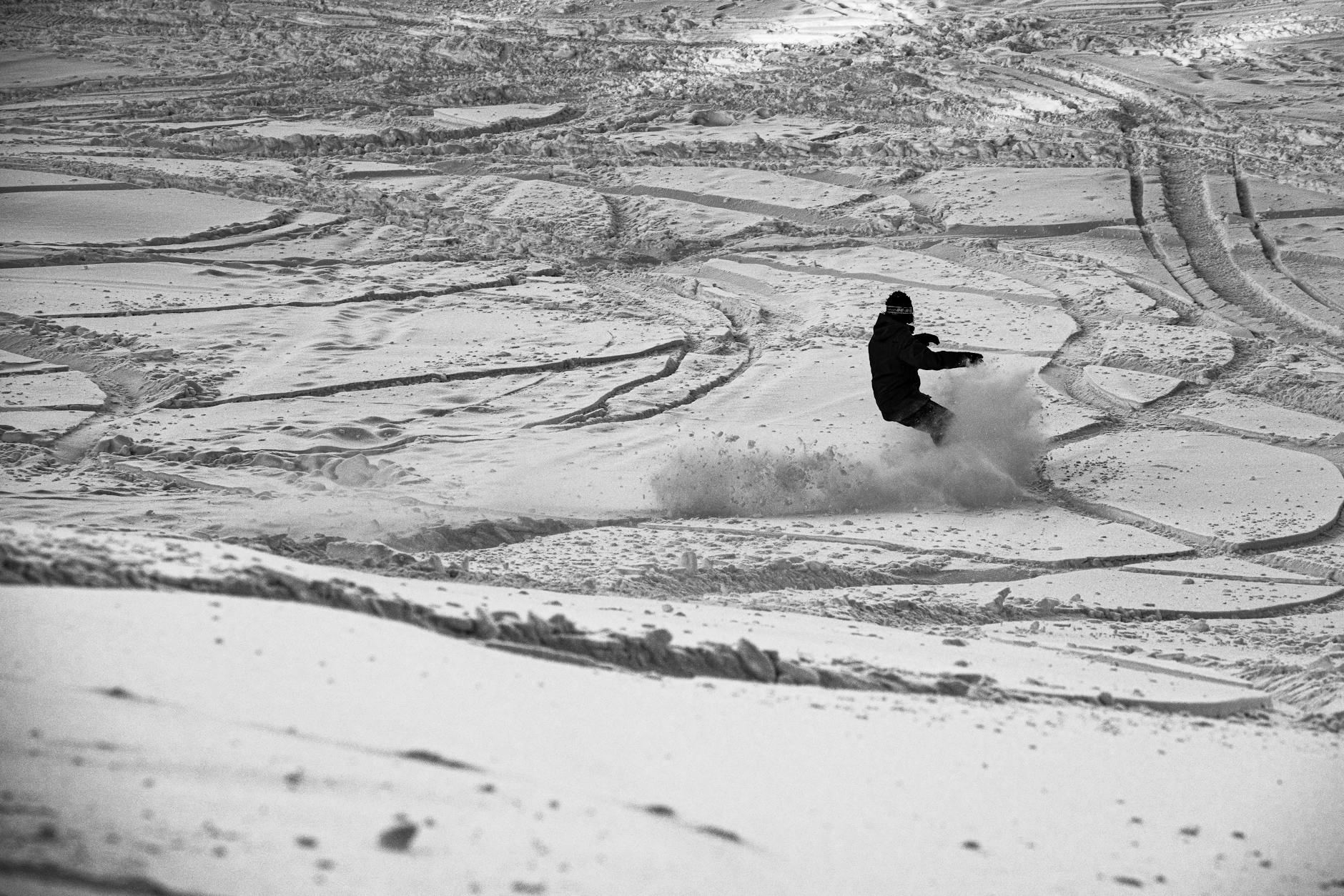 A snowboarder skillfully carves through fresh snow on a winter day, capturing the thrill of the sport.