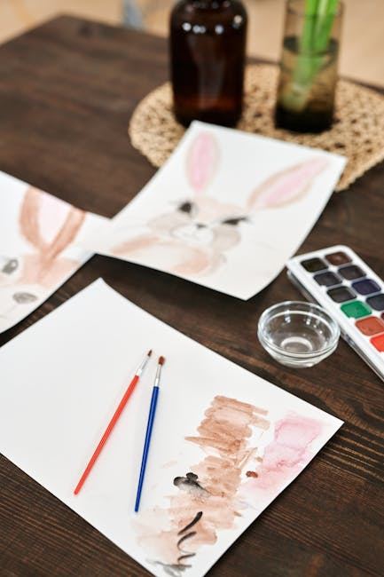 Watercolor supplies and bunny sketches on a wooden table for beginners learning painting techniques.