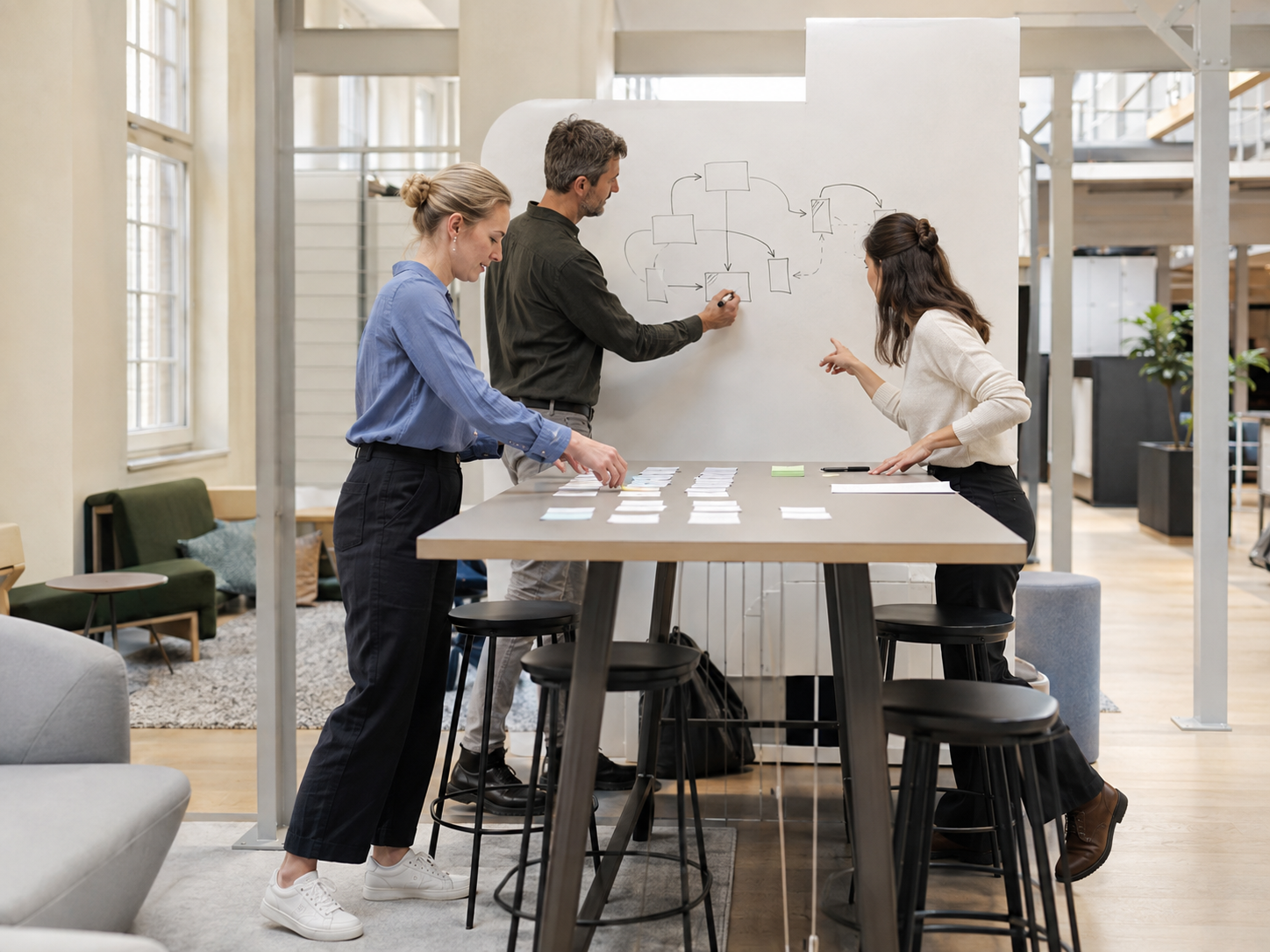 Drei Fachleute entwickeln gemeinsam einen Prozess in einem hellen Workshop-Raum.