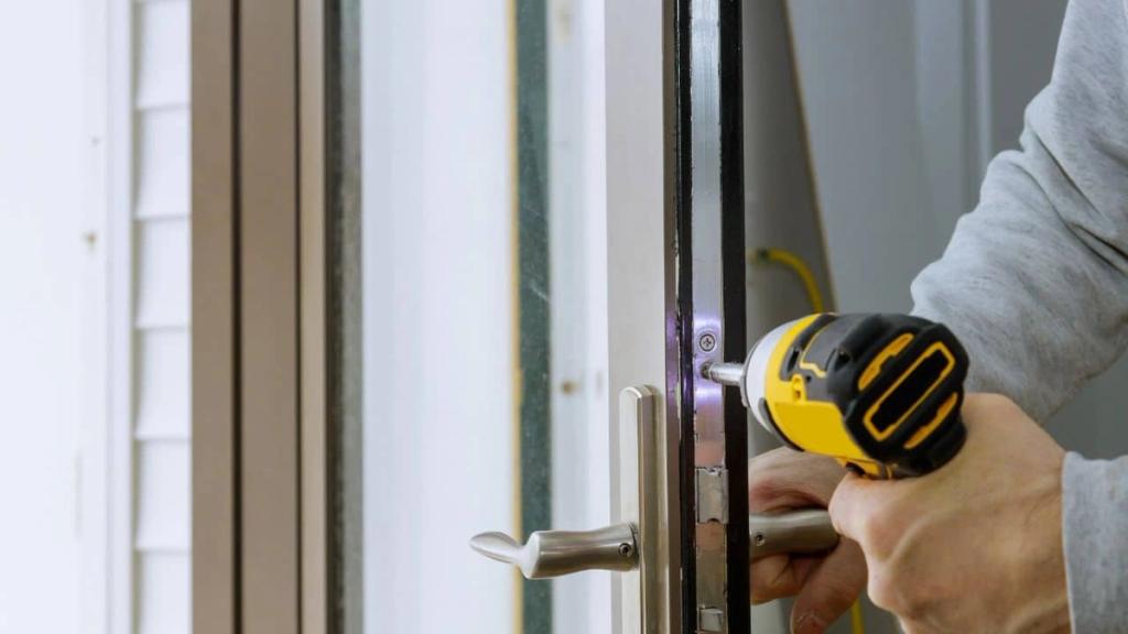 Technician fitting a new lock set on a door with a cordless drill
